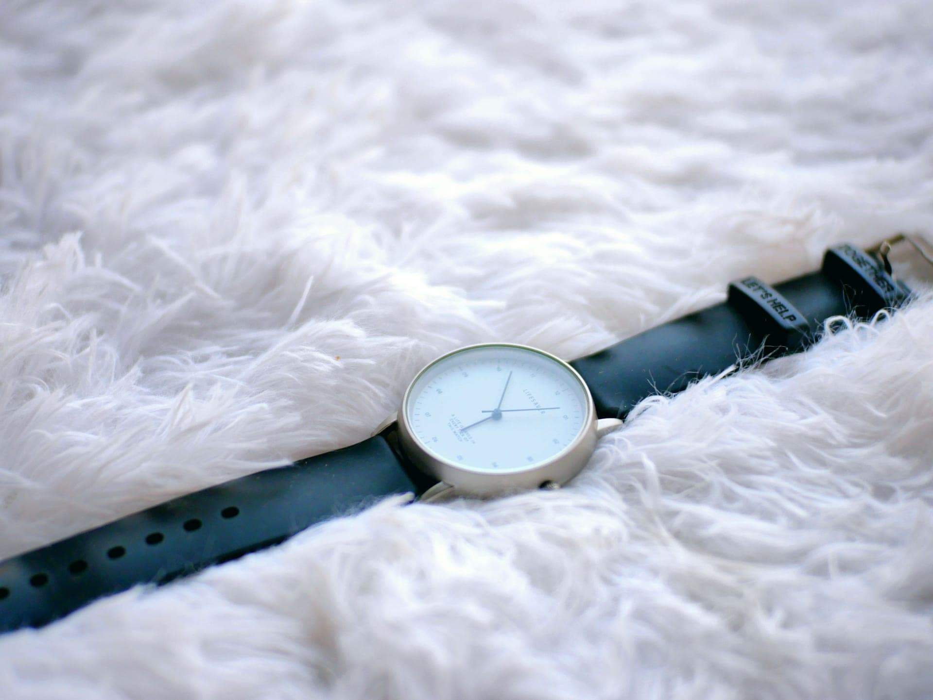 A wristwatch resting on a soft, light neutral surface