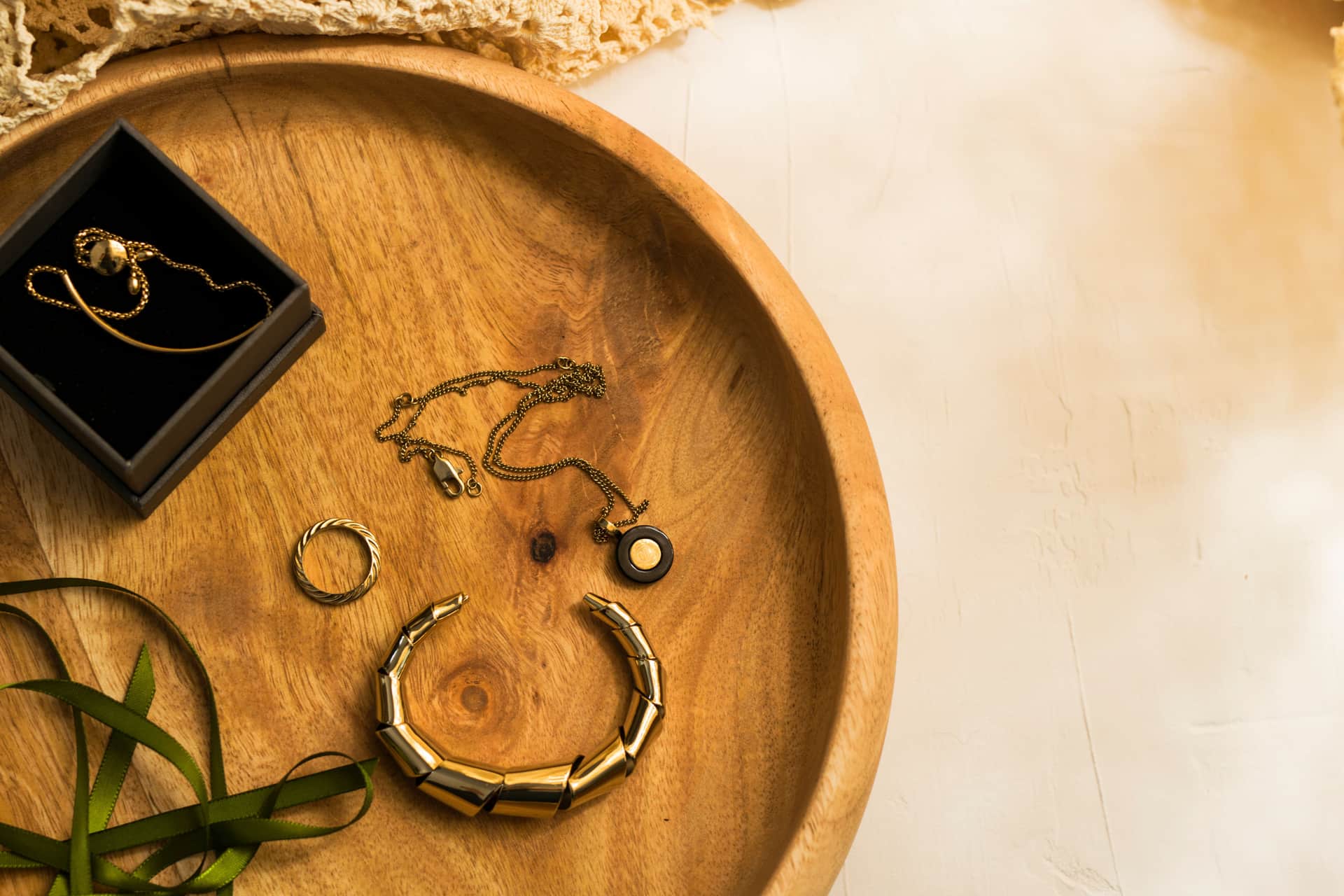A watch resting on a small tray on a bedside surface in morning light