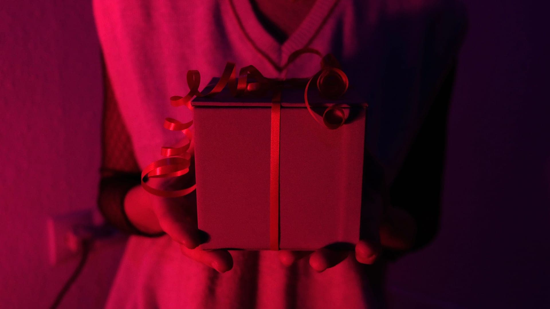A small wrapped gift box held in two hands in soft natural light