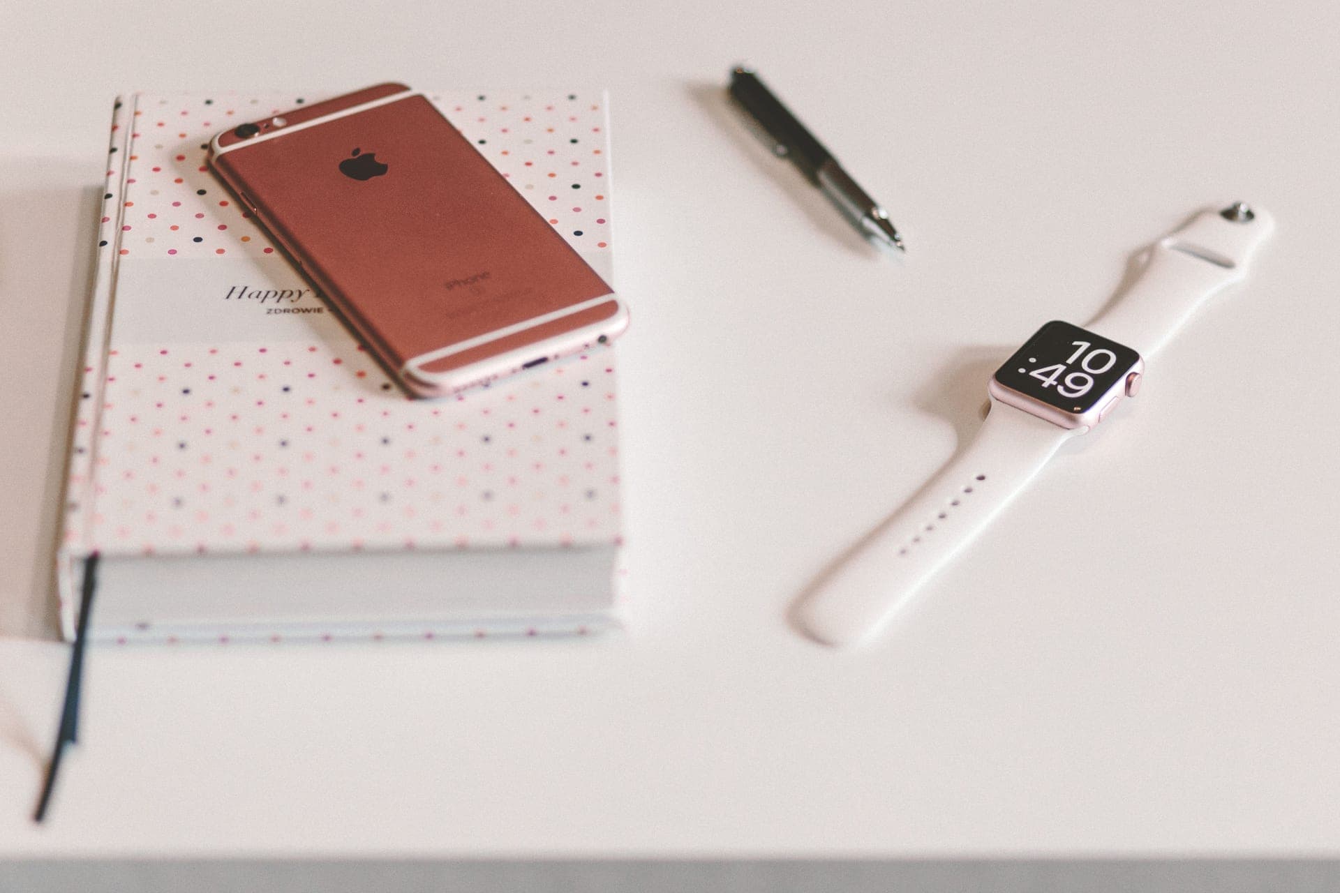 A wristwatch beside an open notebook and pen on a light desk